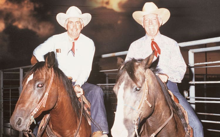 Two men in cowboy hats on horsebacks